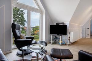 a living room with a tv and chairs and a table at Bäckerhus - Ferienwohnung 4 in Wiek auf Rügen
