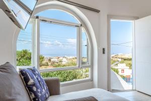 an arched window in a living room with a view of the ocean at Sunset Horizon Villa in Mikonos
