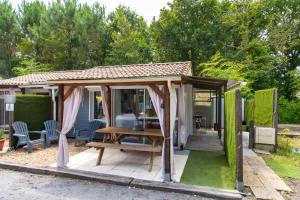 a gazebo with a picnic table in a garden at Chalet B Village Vacances in Gujan-Mestras