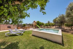 a swimming pool with a chair and a playground at Es Cos in Algaida