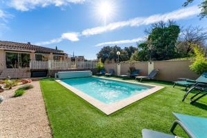 a swimming pool in a yard with grass at La Petite Maison in Bédoin