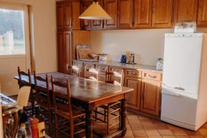 a kitchen with a wooden table and a white refrigerator at La Maison de Melmont in Roumare