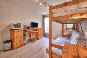 a room with a bunk bed and a desk with a microwave at Prapoutel pied des pistes in Les Adrets