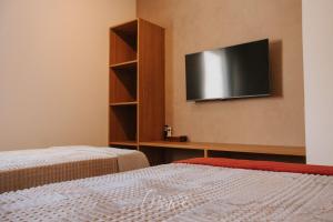 a room with two beds and a television on the wall at Apartamento Verano pé na areia em tatuamunha - NSUN105 in Pôrto de Pedras