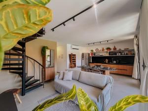 a living room with a couch and a spiral staircase at Apartamento Verano pé na areia em tatuamunha - NSUN105 in Pôrto de Pedras