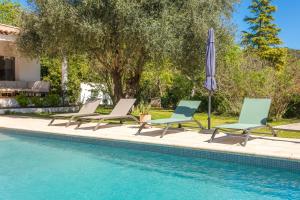 a group of chairs and an umbrella next to a swimming pool at Pomme Reinette in Le Val
