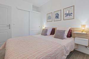 a white bedroom with a large bed and two lamps at Pomme Reinette in Le Val +18 photos