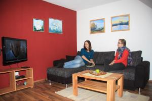 two people sitting on a couch in a living room at Ferienwohnung 'auf dem Burstel' in Kleines Wiesental