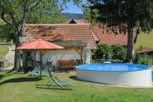 a swimming pool with two chairs and an umbrella at Ferienwohnung 'auf dem Burstel' in Kleines Wiesental