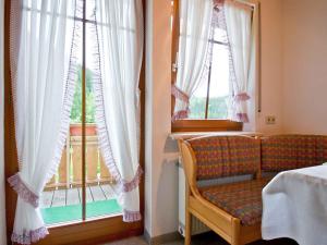 a room with a bed and a window with a chair at Gästehaus Herrmann in Bad Rippoldsau-Schapbach