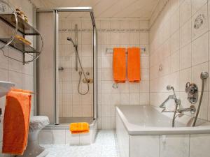 a bathroom with a tub and a shower with orange towels at Gästehaus Herrmann in Bad Rippoldsau-Schapbach