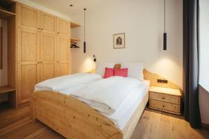 a bedroom with a wooden bed with white sheets and red pillows at Freienfeldhof Pink Lady in Lagundo