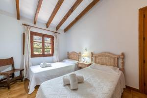 a bedroom with two beds and a chair and a window at Villa La Plana in Pollença +17 photos