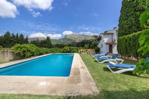a pool with lounge chairs and a house at Villa La Plana in Pollença