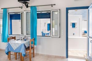 a dining room with a table and blue curtains at Studios Ninemia Serifos 2 in Livadi
