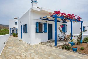 a white house with blue shutters and a patio at Studios Ninemia Serifos 2 in Livadi