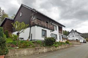 a white house with a balcony on a street at Ferienwohnung Christel in Schmallenberg
