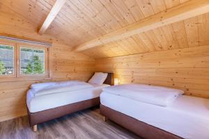 two beds in a room with a wooden ceiling at Chalets Jettweiler in Stockach