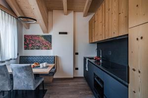 a kitchen with a table and a dining room at Arnica Alpin Lodge in Cavedago