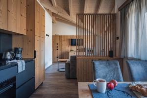 a kitchen with wooden walls and a table and chairs at Arnica Alpin Lodge in Cavedago