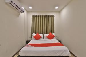a bedroom with a bed with red pillows at Hotel O Ripple Mall in Surat