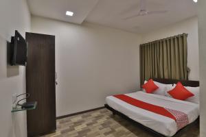 a bedroom with a bed with red pillows and a tv at Hotel O Ripple Mall in Surat +28 photos