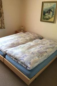 a bed with a comforter on it in a bedroom at Apartment Chalet Steinbock by Interhome in Lenk