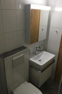 a bathroom with a sink and a toilet and a mirror at Apartment Chalet Steinbock by Interhome in Lenk +1 photo