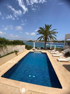 a swimming pool with a palm tree and the water at Casa Vora Mar in Felanitx