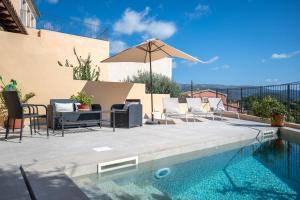 a pool with chairs and an umbrella next to a house at Can Vidal in Campanet