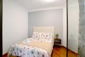 a white bedroom with a bed with pink sheets and pillows at Carmelo y Carmela 2 in Teror