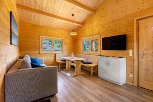 a living room with a couch and a table and a tv at Chalets Jettweiler in Stockach