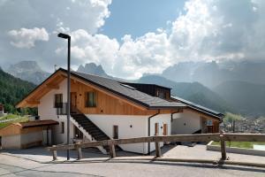 a house with a wooden roof with mountains in the background at Daunëihof in Selva di Val Gardena