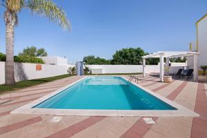 a swimming pool on a patio with a palm tree at Villa Constança in Manta Rota