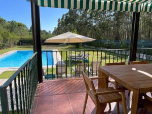 a patio with a table and an umbrella and a pool at Casa dos Pinheiros in Giz