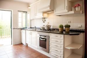 a kitchen with white cabinets and a stove top oven at Casa dos Pinheiros in Giz