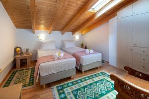 two beds in a room with wooden ceilings at Ria Sweet Home Paxos in Oziás