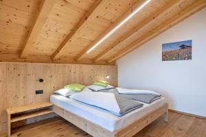 a bed in a room with a wooden ceiling at Parliflhof Apt Laugenblick in Meltina
