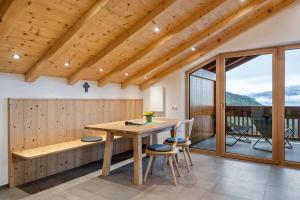 a dining room with a table and chairs and a balcony at Parliflhof Apt Laugenblick in Meltina