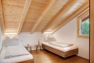 two beds in a room with a wooden ceiling at Alpenloft Meditz in Unterammergau