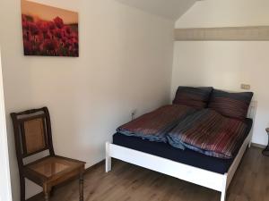a bedroom with a bed and a chair at Ferienhaus Am Fulda Ufer in Rotenburg an der Fulda