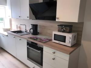 a white kitchen with a microwave and a sink at Ferienhaus Am Fulda Ufer in Rotenburg an der Fulda +13 photos