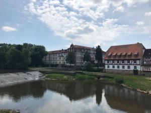 a river in front of a large building with buildings at Ferienhaus Am Fulda Ufer in Rotenburg an der Fulda