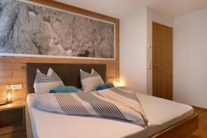 a bedroom with a bed with white sheets and blue pillows at Noreia Pitla in Ortisei