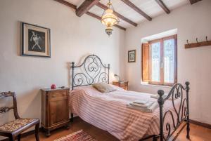 a bedroom with a bed and a chair and a window at Casa Francesca in Montalcino