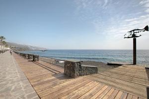 a wooden boardwalk on a beach with the ocean at El Ramonal Vacacional in Candelaria