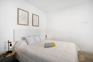 a white bedroom with a large white bed with two pillows at El Ramonal Vacacional in Candelaria
