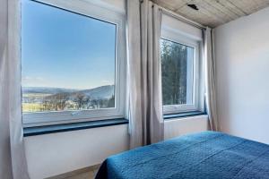 a bedroom with a bed and two large windows at Suiten im Alten Berghotel Franziska in Eslohe