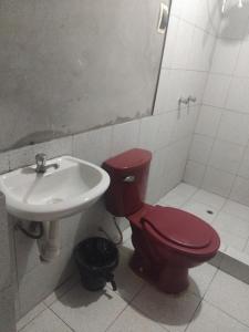 a bathroom with a red toilet and a sink at Casa de huespedes en el centro in Cajamarca