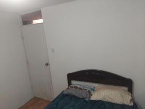 a small bedroom with a bed and a door at Casa de huespedes en el centro in Cajamarca
